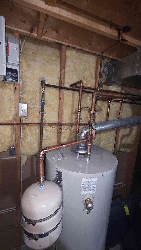 Completed return visit to install 50-gallon residential water heater with necessary code compliance upgrades. Installation included proper copper piping connections, expansion tank mounting, pressure relief valve, venting system, and electrical connections per current code requirements in basement utility area with exposed framing.