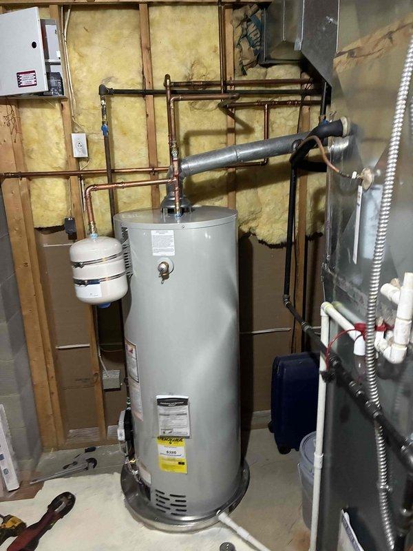 Completed return visit to install 50-gallon residential water heater with necessary code compliance upgrades. Installation included proper copper piping connections, expansion tank mounting, pressure relief valve, venting system, and electrical connections per current code requirements in basement utility area with exposed framing.