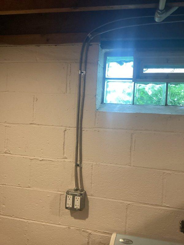 Installed a dedicated electrical circuit for sump pump operation in basement utility area. Ran flexible metal conduit along concrete block wall from panel to new dual GFCI receptacle outlet box, providing code-compliant ground fault protection for the sump pump system.