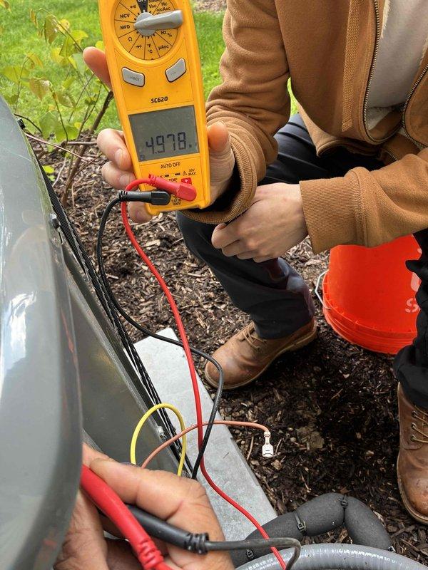 Completed comprehensive cooling system maintenance on residential HVAC unit. Inspected blower assembly and found moderate dust accumulation on squirrel cage fan blades, which was cleaned to restore optimal airflow efficiency. Performed electrical diagnostics on outdoor condensing unit using digital multimeter, verifying voltage readings and confirming proper system operation at 497.8 volts on tested circuit.