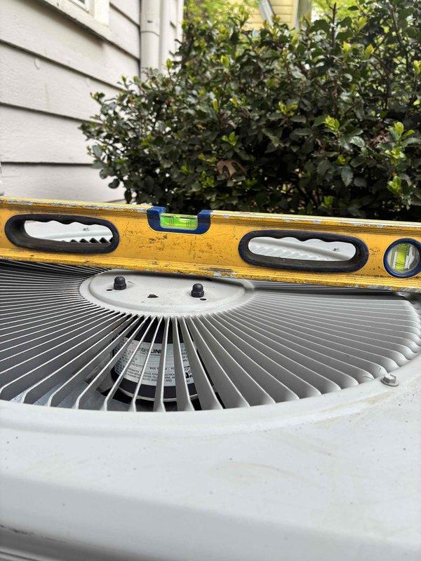 Leveled outdoor condenser unit using gravel base material to ensure proper equipment operation and drainage. Unit was checked with precision level and adjusted to manufacturer specifications for optimal performance and compressor longevity.