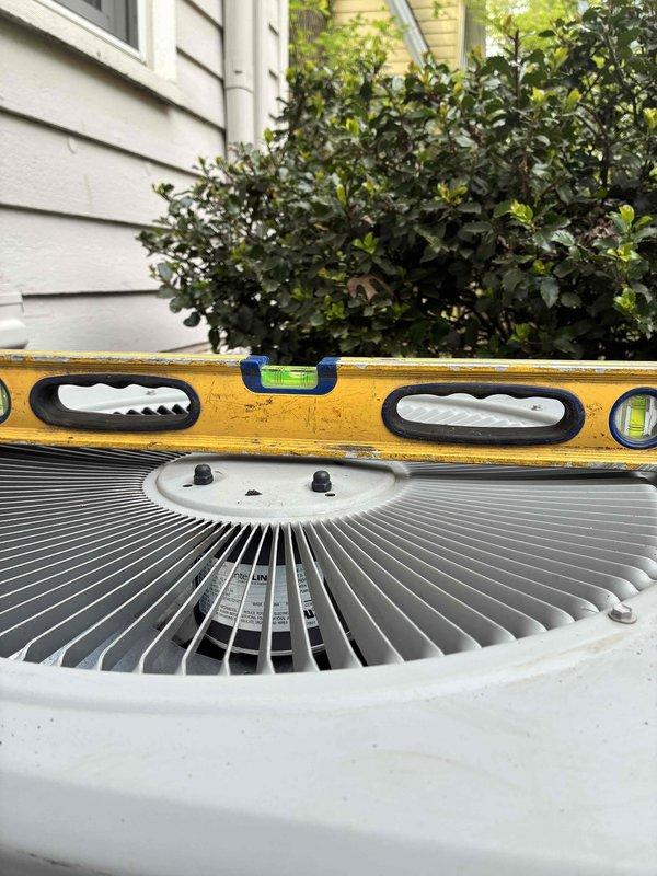 Leveled outdoor condenser unit using gravel base material to ensure proper equipment operation and drainage. Unit was checked with precision level and adjusted to manufacturer specifications for optimal performance and compressor longevity.