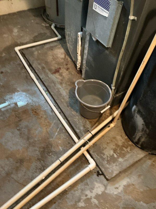 Responded to service call for reported furnace leak. Upon arrival, found significant water accumulation and staining on basement floor surrounding HVAC unit. Inspected furnace and identified failed condensate drainage system as source of water intrusion. Placed collection bucket to contain active dripping while assessing extent of damage. Photographed water damage patterns on concrete floor and traced condensate line routing. Recommended immediate condensate pump replacement or drain line clearing to prevent further water damage to basement floor and potential secondary heat exchanger issues from improper drainage.