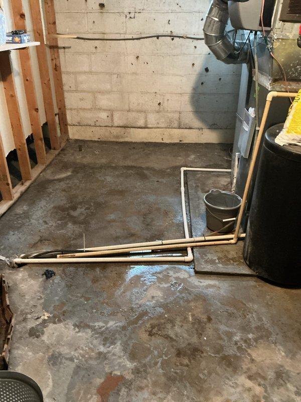 Responded to service call for reported furnace leak. Upon arrival, found significant water accumulation and staining on basement floor surrounding HVAC unit. Inspected furnace and identified failed condensate drainage system as source of water intrusion. Placed collection bucket to contain active dripping while assessing extent of damage. Photographed water damage patterns on concrete floor and traced condensate line routing. Recommended immediate condensate pump replacement or drain line clearing to prevent further water damage to basement floor and potential secondary heat exchanger issues from improper drainage.
