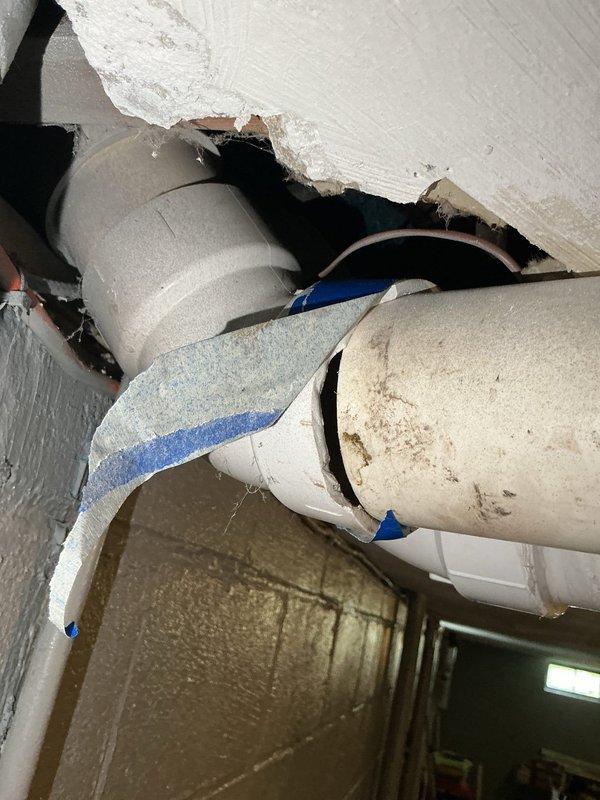 Responded to customer report of hole in pipe connected to furnace system. Upon inspection, discovered damaged drywall/ceiling material with exposed PVC venting pipes from furnace exhaust system. Documented existing conditions showing white PVC vent pipes with compromised ceiling access point and structural opening requiring attention. Assessed plumbing and venting infrastructure in crawl space area, noting PVC drainage/ventilation components with support strapping in place. Customer made aware of findings and photographic documentation completed for repair planning purposes.