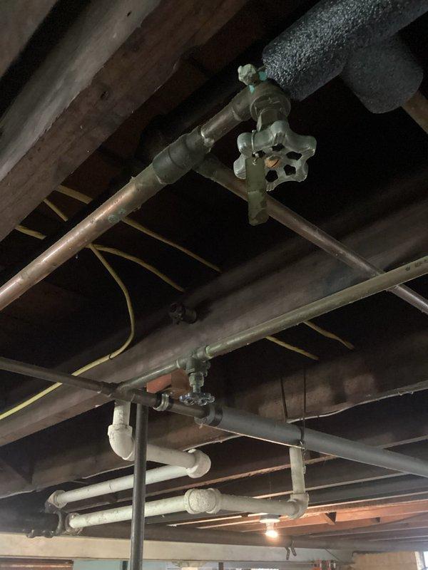 Conducted comprehensive plumbing inspection of residential basement and crawl space areas, documenting existing plumbing infrastructure including copper supply lines with shut-off valves, PVC drainage systems, and insulated piping. Assessed condition of mechanical components, noting wall-mounted copper piping with mounting brackets, multiple valve assemblies, and evidence of moisture-related deterioration on concrete block walls requiring future monitoring.