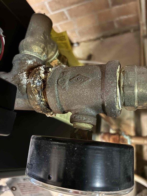 Returned to site to replace failed igniter on boiler system and repair leaking pipes in vicinity of boiler. Upon inspection, identified severely corroded pressure relief valve with significant mineral buildup and rust at threaded connections, which was the source of active leaking. Replaced defective igniter to restore proper boiler ignition sequence. Addressed multiple pipe leaks by replacing corroded valve assembly and repairing compromised copper piping connections with new brass fittings. System tested and verified operational with no further leaks detected at completion.