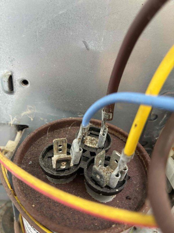 Completed cooling tune-up on outdoor condensing unit. Inspected electrical connections at capacitor terminals, noting age-related corrosion and oxidation on terminal points and wiring. Verified all wire connections secure, tested capacitor functionality, and confirmed proper operation of condenser fan assembly. Unit operating within normal parameters upon completion of maintenance inspection.