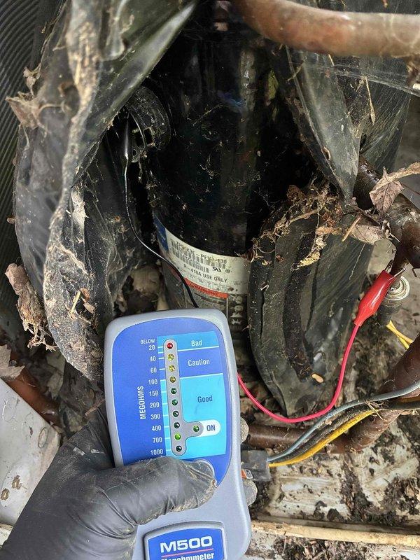 Completed comprehensive HVAC cooling system maintenance on outdoor condensing unit. Performed insulation resistance testing on compressor using megohmmeter to verify electrical integrity and proper motor winding insulation, with readings indicating acceptable operational parameters. Noted significant accumulation of dirt, debris, spider webs, and organic matter on compressor housing and surrounding components requiring attention for optimal system performance and airflow efficiency.
