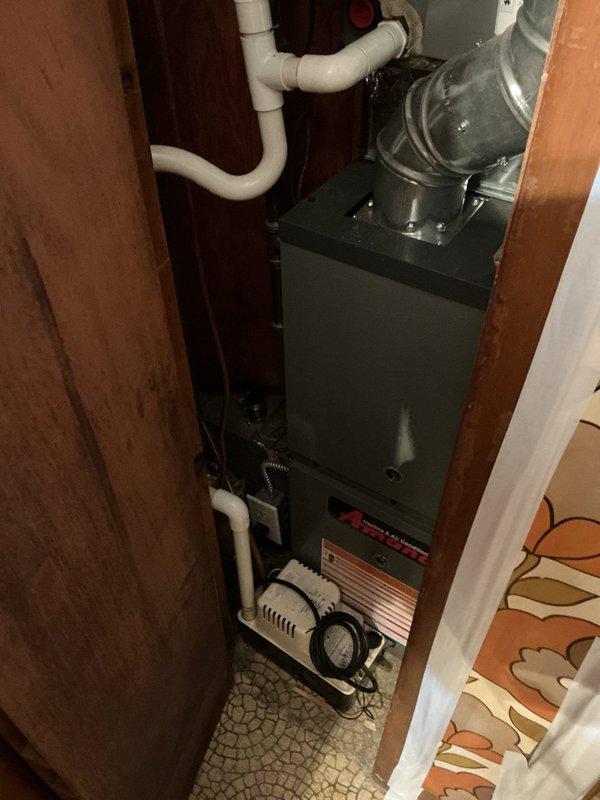 Responded to service call for residential furnace producing loud noise during operation. Upon arrival, inspected Amana furnace unit installed in closet-style cabinet configuration. Conducted thorough visual and operational assessment of furnace, blower motor assembly, ductwork connections, and associated components including humidifier and PVC venting system. Verified system functionality and identified source of noise concern. Unit found to be operating properly with all safety controls functioning as designed. Documented equipment condition with photographic evidence showing complete installation including furnace cabinet, air handler, metallic ductwork, and auxiliary components.