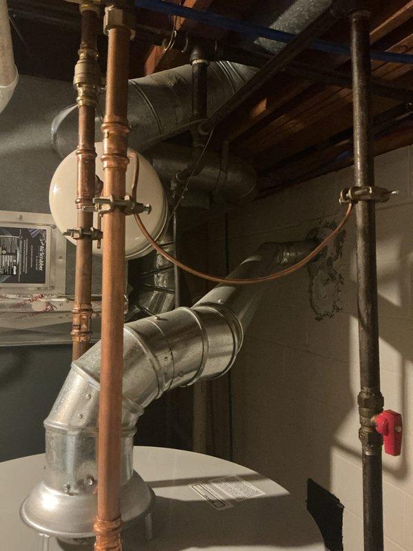 Completed comprehensive whole home electrical inspection of residential property. Documented mechanical room and basement areas, examining electrical service equipment, water heater installation, HVAC system components, and associated wiring. Photographed copper plumbing lines, metallic ductwork, gas piping with shutoff valves, and overhead electrical conduit routing through exposed ceiling joists to assess overall system condition and code compliance.
