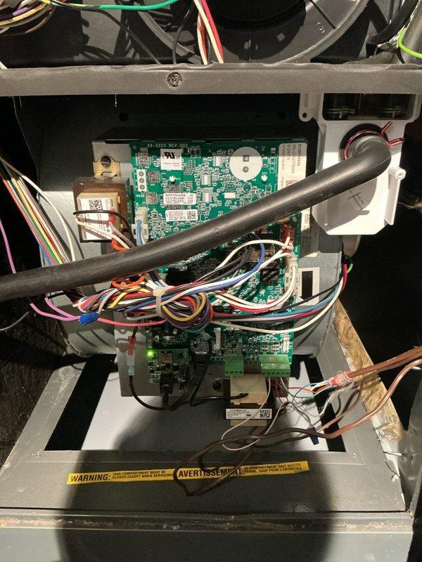 Responded to no heat call on residential furnace system. Upon arrival, accessed control compartment and inspected integrated furnace control board, blower assembly, and gas valve connections. Examined circuit board assembly with multiple wire harnesses and verified electrical connections throughout the system. Inspected gas valve assembly with copper piping connections and confirmed proper routing of all colored wiring to control components. Checked blower motor, capacitor, and all safety circuits. Photographed control board configuration and gas valve assembly for documentation. System components appeared properly installed with secure wire connections and intact safety labels. Completed diagnostic inspection of furnace interior including all electrical connections, gas train components, and control circuitry to identify cause of no heat condition.