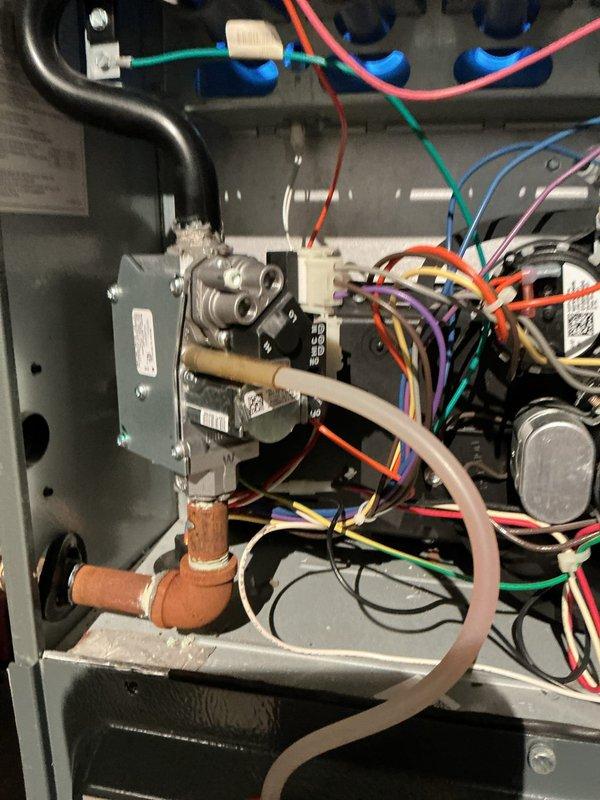 Responded to no heat call on residential furnace system. Upon arrival, accessed control compartment and inspected integrated furnace control board, blower assembly, and gas valve connections. Examined circuit board assembly with multiple wire harnesses and verified electrical connections throughout the system. Inspected gas valve assembly with copper piping connections and confirmed proper routing of all colored wiring to control components. Checked blower motor, capacitor, and all safety circuits. Photographed control board configuration and gas valve assembly for documentation. System components appeared properly installed with secure wire connections and intact safety labels. Completed diagnostic inspection of furnace interior including all electrical connections, gas train components, and control circuitry to identify cause of no heat condition.