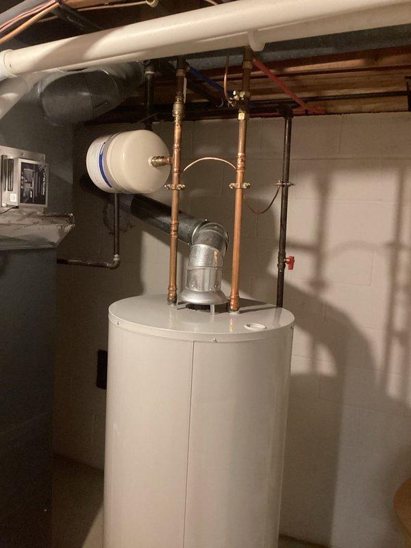 Responded to report of leaking valve at bottom of hot water heater that would not close properly. Upon inspection, identified faulty drain valve on residential water heater allowing water to seep from base of unit. Documented existing plumbing configuration including copper supply lines, expansion tank, and standard residential hot water heating setup for service records.