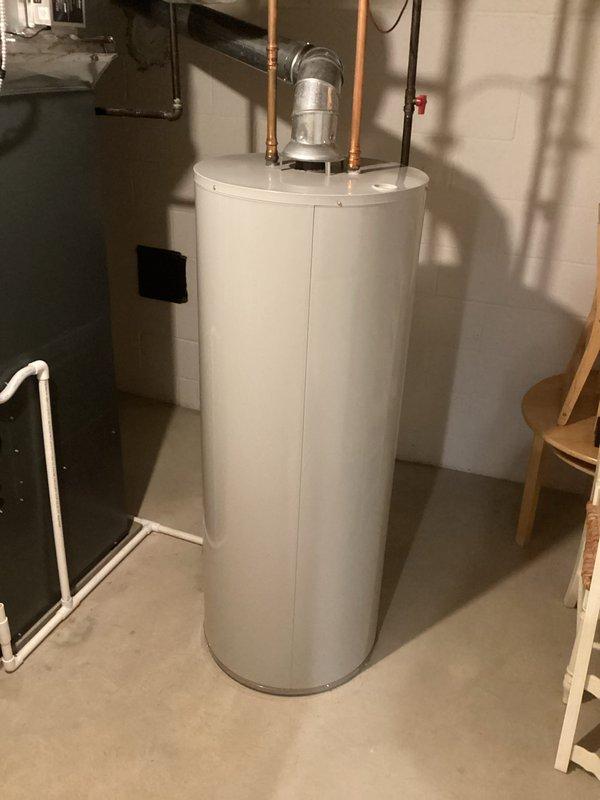 Responded to report of leaking valve at bottom of hot water heater that would not close properly. Upon inspection, identified faulty drain valve on residential water heater allowing water to seep from base of unit. Documented existing plumbing configuration including copper supply lines, expansion tank, and standard residential hot water heating setup for service records.