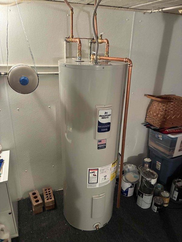 Completed installation of 50-gallon Bradford White residential water heater in basement utility area. Connected copper supply and discharge lines with proper shutoff valves, installed expansion tank with appropriate fittings, and secured unit per manufacturer specifications. All plumbing connections tested and verified operational with no leaks detected.