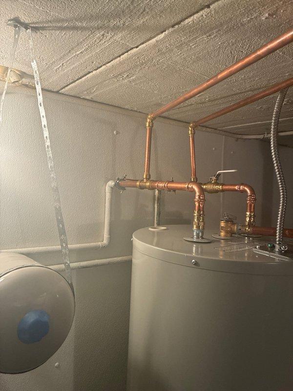 Completed installation of 50-gallon Bradford White residential water heater in basement utility area. Connected copper supply and discharge lines with proper shutoff valves, installed expansion tank with appropriate fittings, and secured unit per manufacturer specifications. All plumbing connections tested and verified operational with no leaks detected.