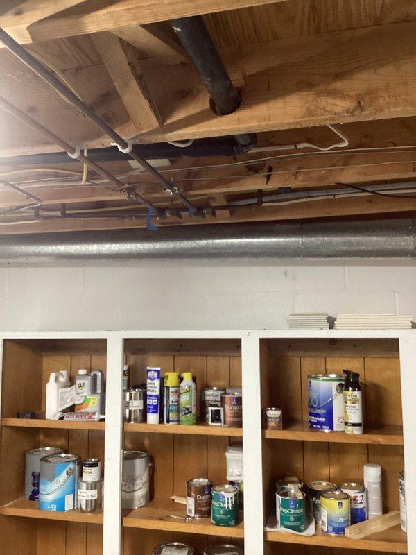 Completed plumbing inspection of basement utility area to assess gas line installation requirements. Documented existing mechanical systems, including furnace, water heater, water treatment equipment, and current pipe routing through ceiling joists to determine optimal path and materials needed for new gas line installation.