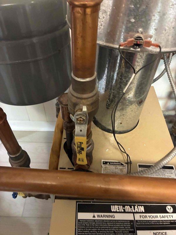 Responded to service call for non-operational boiler system. Upon inspection, identified water leak at copper piping connections near expansion tank and Weil-McLain boiler unit. Examined plumbing assembly including vertical copper risers, brass fittings, and shut-off valve with pressure regulator, noting moisture accumulation on galvanized expansion tank surface and oxidation on copper pipes indicating chronic leak condition. Tightened connections, tested system operation, and verified boiler restored to proper working condition with no active leaking.