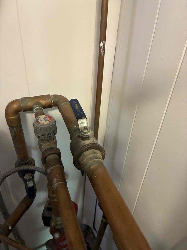Responded to service call for non-operational boiler system. Upon inspection, identified water leak at copper piping connections near expansion tank and Weil-McLain boiler unit. Examined plumbing assembly including vertical copper risers, brass fittings, and shut-off valve with pressure regulator, noting moisture accumulation on galvanized expansion tank surface and oxidation on copper pipes indicating chronic leak condition. Tightened connections, tested system operation, and verified boiler restored to proper working condition with no active leaking.