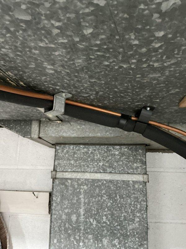 Completed scheduled cooling system maintenance inspection in residential basement mechanical room. Performed visual assessment of HVAC equipment, ductwork connections, and associated utility infrastructure including copper refrigerant lines, galvanized ductwork, and pipe supports. Verified proper installation of mechanical components, checked insulation coverage on ceiling-mounted piping, and confirmed structural integrity of wall-mounted duct sections and pipe hangers. Documented equipment conditions through photographic records for maintenance history files.
