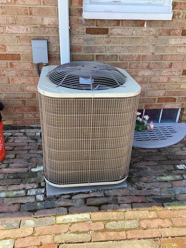 Performed comprehensive cooling season maintenance on residential Payne brand air conditioning system. Inspected condensing unit exterior components including fan assembly, protective grille, condenser coil housing with vertical fins, and electrical connections at wall-mounted junction box. Verified proper unit clearances, stable mounting on brick paver foundation, and refrigerant line connections along exterior wall, confirming system operational readiness for cooling season.