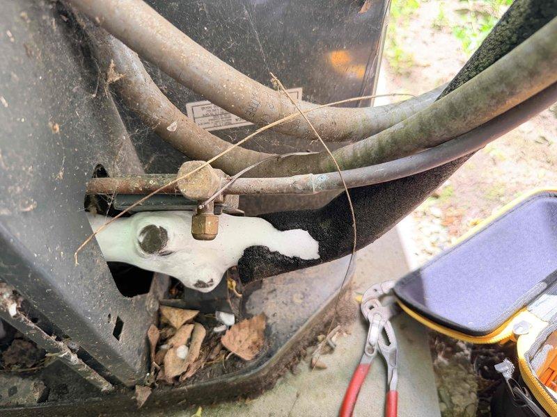 Responded to no cooling complaint on 10-15 year old central air conditioning system. Upon arrival, customer reported indoor fan operating but no cold air delivery to living space and inability to reach temperature setpoint. Performed diagnostic evaluation of outdoor condensing unit and observed significant debris accumulation in equipment base including leaves and organic matter. Inspected electrical disconnect, refrigerant line connections, and conduit routing along foundation. Noted weathering and corrosion on exterior components consistent with unit age and outdoor exposure. Assessed condenser operation, electrical connections, and overall system condition to determine root cause of cooling failure and provided recommendations for necessary repairs to restore proper system function.