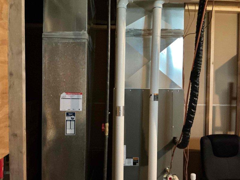 Responded to no cooling complaint on residential air conditioning system. Upon arrival, performed diagnostic inspection of HVAC equipment including furnace/air handler unit and associated components. Inspected condensate drain system with PVC piping, verified proper installation of safety switches and pressure relief mechanisms. Documented equipment condition through photographic records showing furnace cabinet, ductwork connections, copper refrigerant lines, and auxiliary components in mechanical space.
