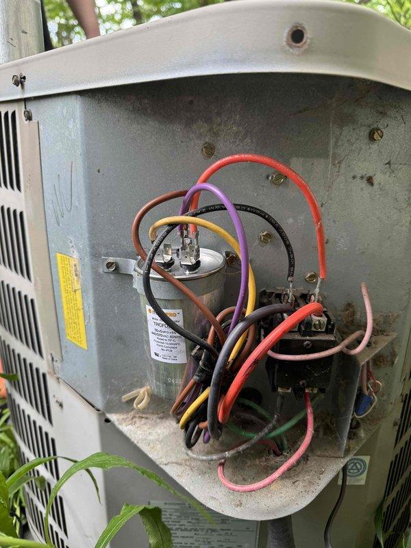 Responded to no cooling call on 10+ year old outdoor condensing unit. Upon arrival, found unit not operating and surrounded by overgrown vegetation restricting airflow. Removed access panel and inspected electrical components including capacitor and wiring connections. Unit showed signs of age with dirt and debris accumulation in compartment. Documented equipment condition with photos showing compromised airflow due to vegetation encroachment and recommended clearing around unit for proper operation and future maintenance access.
