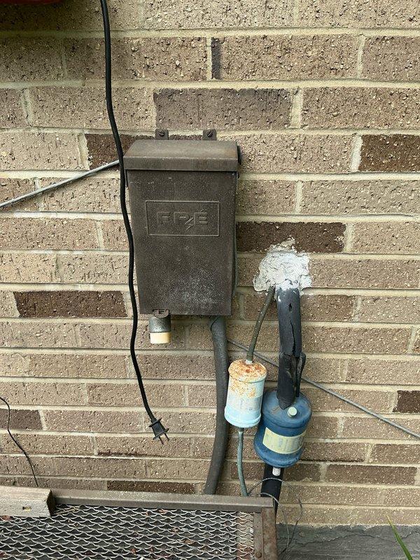 Conducted site evaluation and provided AC replacement options for residential property. Documented existing exterior electrical junction box, plumbing components including water filter with visible corrosion, and outdoor utility installations mounted on brick exterior wall. Assessed current system configuration and prepared comprehensive replacement recommendations based on site conditions and equipment accessibility.