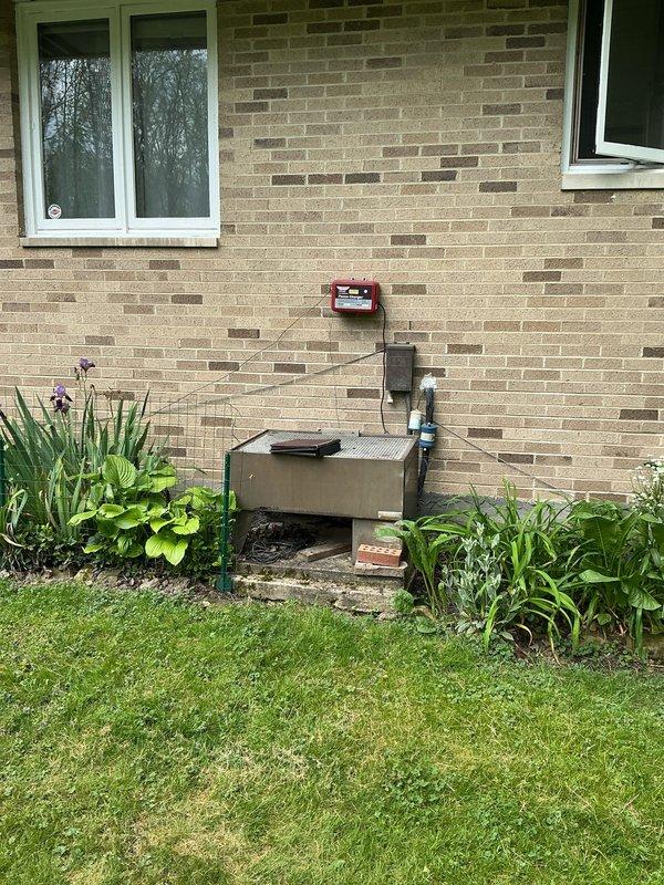 Conducted site evaluation and provided AC replacement options for residential property. Documented existing exterior electrical junction box, plumbing components including water filter with visible corrosion, and outdoor utility installations mounted on brick exterior wall. Assessed current system configuration and prepared comprehensive replacement recommendations based on site conditions and equipment accessibility.