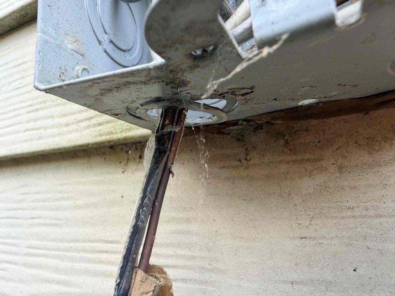 Responded to emergency no cooling call for central air conditioning system. Upon arrival, discovered severely deteriorated electrical wiring and damaged conduit at exterior disconnect box serving the outdoor condensing unit. Wire insulation had completely disintegrated, exposing internal conductors with evidence of charring and weather damage. Junction box showed signs of corrosion and the electrical connection posed an immediate safety hazard. Documented extensive wire damage with photographs showing compromised insulation, exposed conductors, and deteriorated protective sheathing. Advised customer that the damaged electrical supply wiring required immediate replacement before air conditioning system could be safely restored to operation.