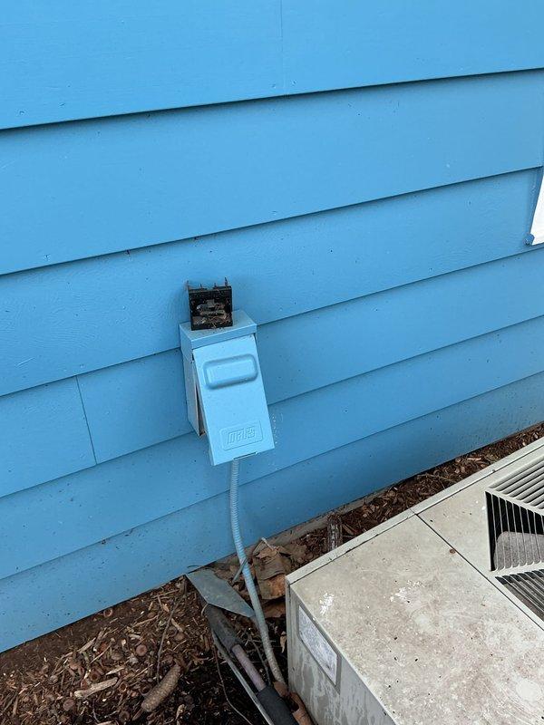 Responded to no cooling complaint with thermostat communication issue. Upon arrival, found outdoor condensing unit installed on mulch bed against building exterior with visible weathering and damaged electrical connection box showing signs of deterioration at conduit entry point. Inspected system components, documented equipment condition including refrigerant line connections and manufacturer specifications, and assessed thermostat communication failure preventing compressor operation.