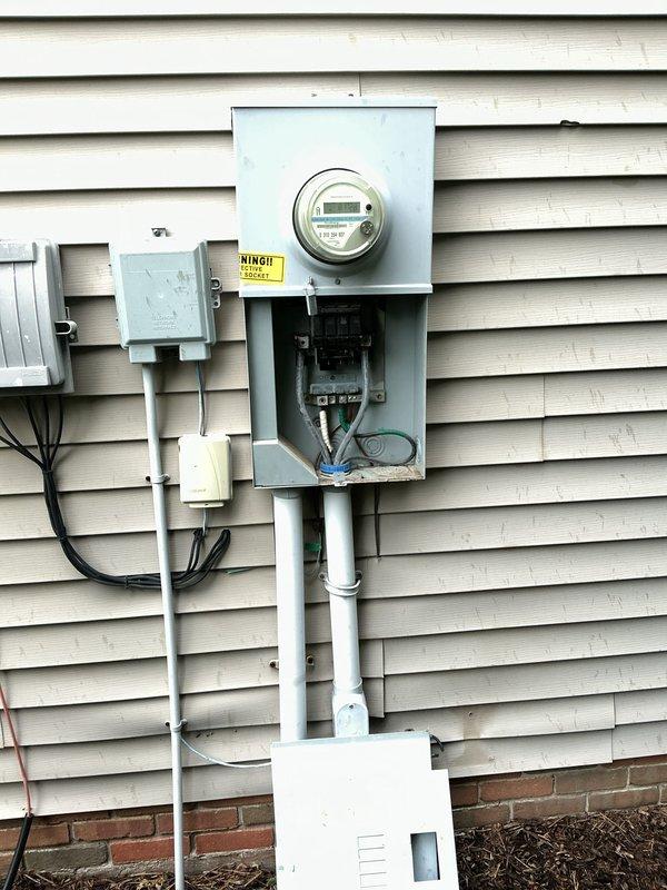 Performed comprehensive whole home electrical inspection of residential service entrance and main distribution equipment. Documented exterior meter installation, including digital smart meter, main service panel, and associated conduit runs from meter base to foundation level. Inspected and photographed main disconnect panel containing four-circuit breaker configuration with visible bus bar connections and service entrance conductors. Noted weathering and oxidation on bus bar terminals and mounting hardware consistent with outdoor installation age. Verified proper conduit routing, grounding conductor installation, and wire management through panel grommet. All findings documented with detailed photographic evidence for client records.