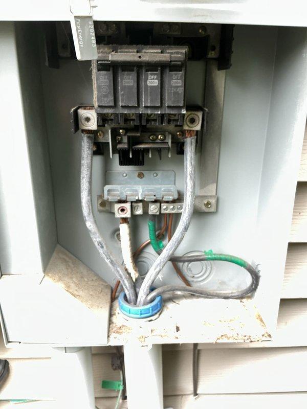 Performed comprehensive whole home electrical inspection of residential service entrance and main distribution equipment. Documented exterior meter installation, including digital smart meter, main service panel, and associated conduit runs from meter base to foundation level. Inspected and photographed main disconnect panel containing four-circuit breaker configuration with visible bus bar connections and service entrance conductors. Noted weathering and oxidation on bus bar terminals and mounting hardware consistent with outdoor installation age. Verified proper conduit routing, grounding conductor installation, and wire management through panel grommet. All findings documented with detailed photographic evidence for client records.