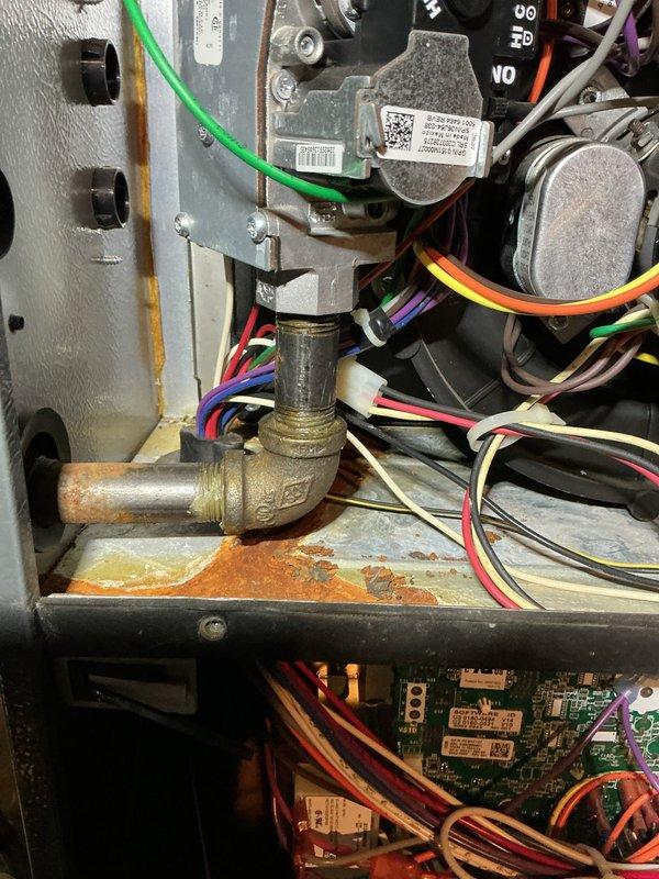 Responded to no cooling call and performed system diagnostics. Upon inspection, discovered significant corrosion and oxidation on gas valve assembly and surrounding components, indicating moisture intrusion and potential safety concerns. Documented conditions with photographic evidence showing deteriorated brass fittings, rust deposits on base pan, and compromised electrical connections that required immediate attention to restore safe system operation.