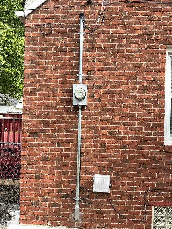 Completed comprehensive whole-home electrical inspection including exterior service entrance and main distribution panel. Documented electrical service mast, meter base, and exterior panel box mounted on brick exterior wall, verifying proper installation and condition of overhead service connection. Inspected interior main breaker panel in basement utility area, evaluating all circuit breakers, wire routing, conductor terminations, and overall panel configuration for code compliance and safety concerns.