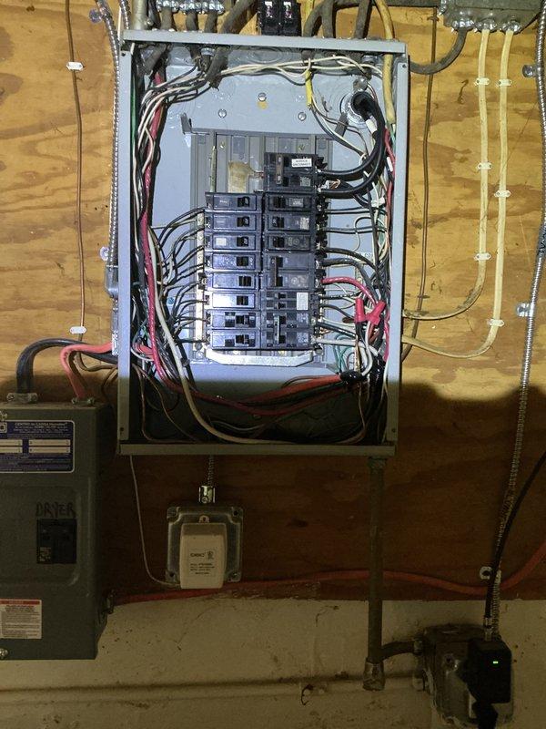 Completed comprehensive whole-home electrical inspection including exterior service entrance and main distribution panel. Documented electrical service mast, meter base, and exterior panel box mounted on brick exterior wall, verifying proper installation and condition of overhead service connection. Inspected interior main breaker panel in basement utility area, evaluating all circuit breakers, wire routing, conductor terminations, and overall panel configuration for code compliance and safety concerns.