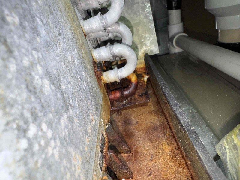 # HVAC Cooling Maintenance Completed

Performed comprehensive cooling system maintenance on residential HVAC unit. Upon inspection, discovered evaporator coil completely covered in thick frost and ice buildup, indicating restricted airflow or refrigerant system abnormality. Identified significant corrosion and rust on pipe mounting brackets and hardware at condensate drain assembly, with visible water damage and staining on surrounding floor surfaces suggesting chronic moisture issues or previous drain line failures. Documented system conditions including compromised drainage components and frozen evaporator coil requiring immediate attention to prevent compressor damage and restore proper cooling operation.