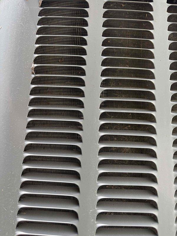 Performed comprehensive cooling system maintenance on HVAC unit. Completed inspection of blower assembly and squirrel cage fan wheel, noting normal dust accumulation on blades and housing. Examined ventilation grille and louver panel, observing expected dirt and debris buildup within recessed openings. Delivered replacement air filter and batteries for outdoor temperature sensor as requested. System operational and ready for cooling season.