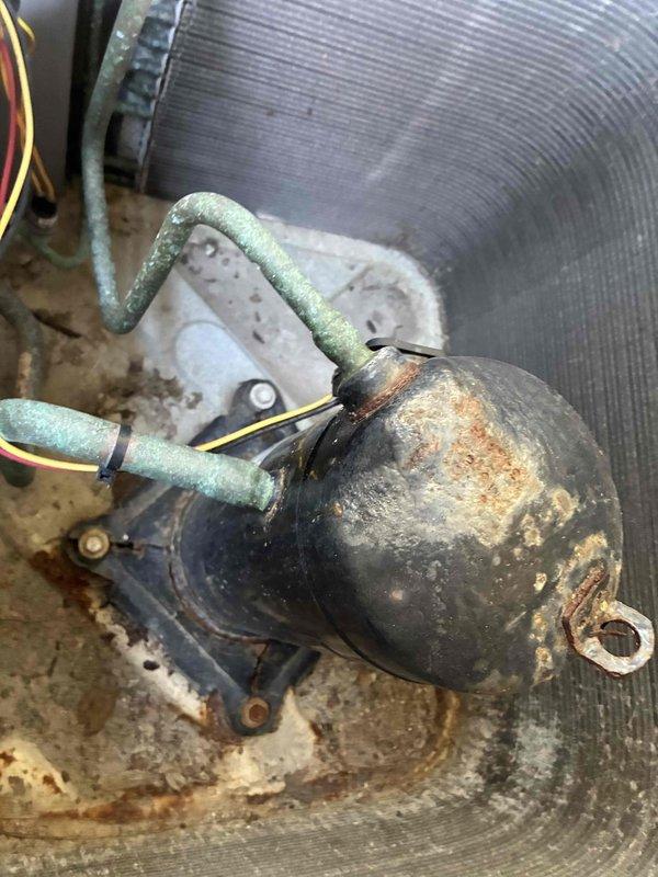 Returned to unit after previous dye injection to conduct leak search on HVAC system. Performed thorough inspection of compressor and refrigerant lines using UV light detection method. Documented current system conditions including temperature readings of 73.1°F and visual evidence of component deterioration. Identified heavily corroded compressor housing with significant rust accumulation and oxidation present on copper refrigerant lines. Captured photographic documentation of leak search findings and overall equipment condition for service records.