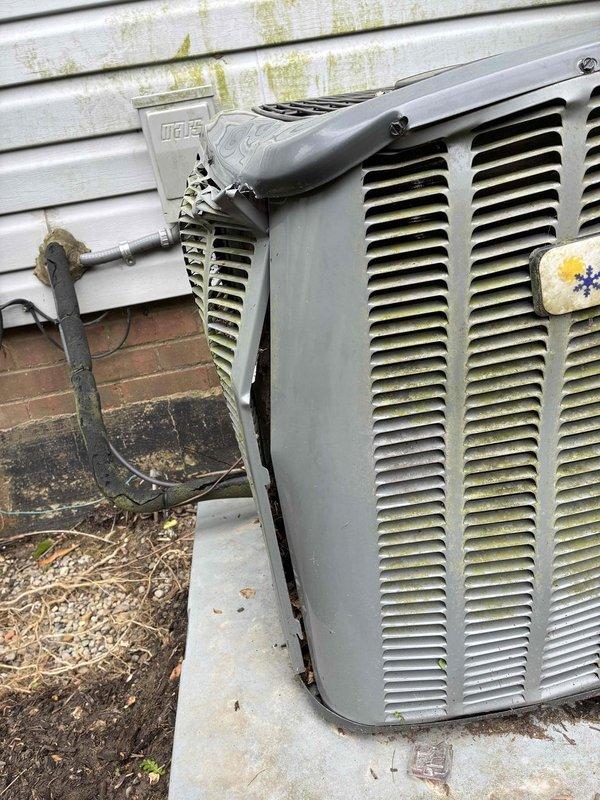 Responded to service call for air conditioning unit damaged by ice accumulation. Upon arrival, inspected outdoor condenser unit and found weathered housing with accumulated dirt and debris on louvered grilles and fan assembly. Assessed refrigerant lines, electrical connections, and overall system condition following ice-related damage. Documented equipment condition with photographs showing three-blade fan assembly, protective wire grille, and exterior components. Unit operational after inspection, with customer advised of findings.
