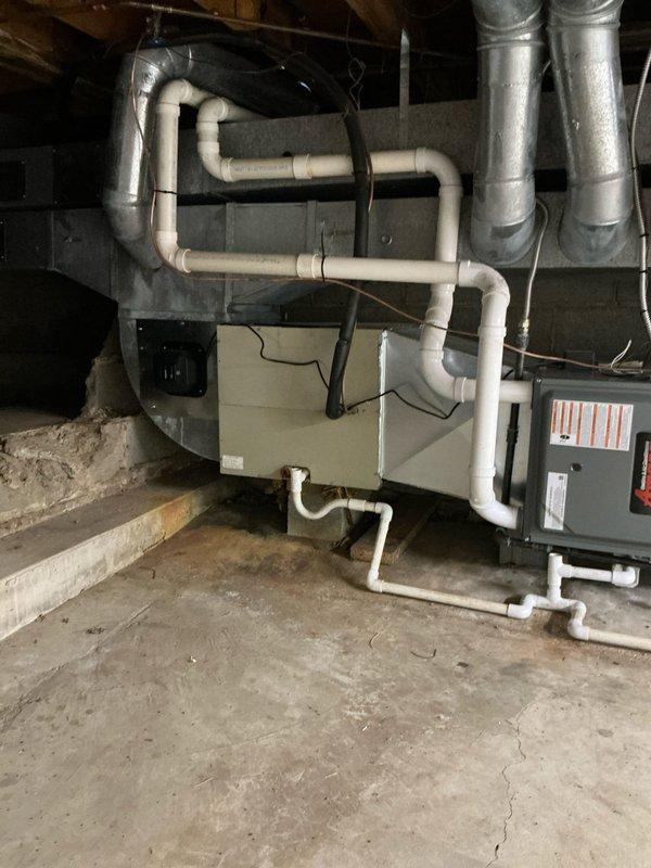 Completed comprehensive HVAC system replacement in residential basement mechanical room. Installed new air handler unit with associated condensate drainage system featuring multiple PVC drain lines with proper pitch and routing. Configured metallic ductwork connections to integrate with existing distribution system, ensuring proper airflow pathways. Installed furnace unit with appropriate electrical connections and safety controls. All equipment positioned on concrete slab with adequate clearances for service access and code compliance.