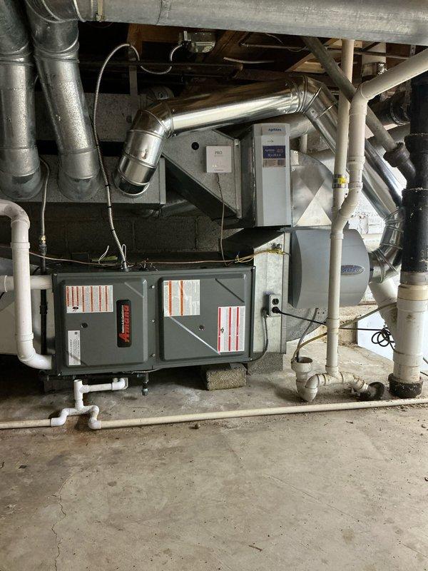 Completed comprehensive HVAC system replacement in residential basement mechanical room. Installed new air handler unit with associated condensate drainage system featuring multiple PVC drain lines with proper pitch and routing. Configured metallic ductwork connections to integrate with existing distribution system, ensuring proper airflow pathways. Installed furnace unit with appropriate electrical connections and safety controls. All equipment positioned on concrete slab with adequate clearances for service access and code compliance.