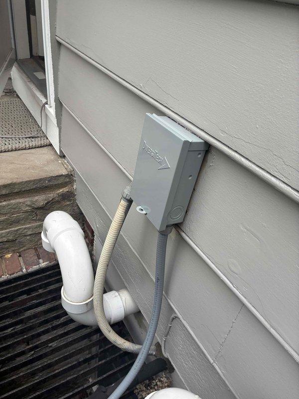 Completed installation of new residential air conditioning system. Mounted outdoor condensing unit on gravel pad adjacent to home exterior, installed electrical disconnect box with proper conduit connections, and routed refrigerant lines with brass service valves and appropriate insulation. Installed white PVC condensate drain line with proper pitch and termination, verified refrigerant charge levels per manufacturer specifications, and ensured all electrical and mechanical connections meet code requirements for safe operation.
