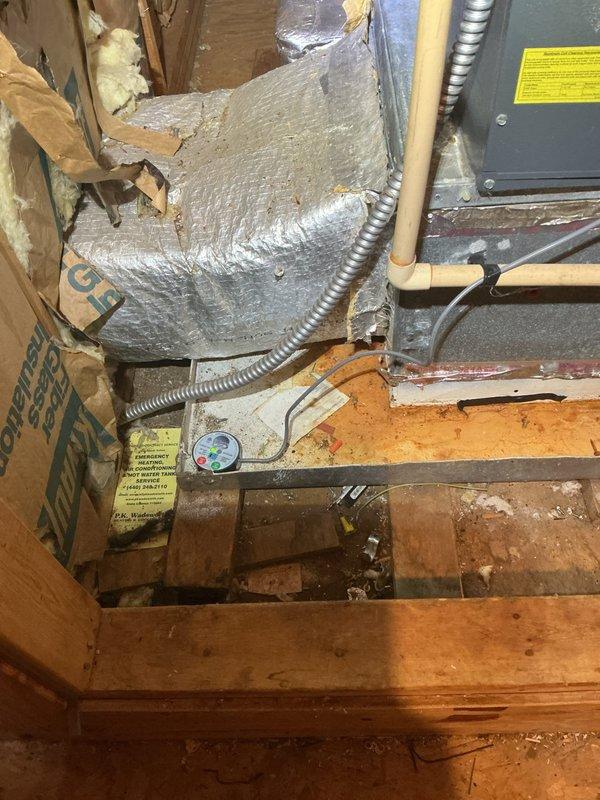 Responded to emergency no cooling call for ductless mini-split system approximately 6-9 years old. Upon arrival, customer reported unit blowing weak warm air with no cooling capacity. Performed diagnostic inspection of indoor air handler located in basement utility area and outdoor condensing unit. Inspected electrical connections at junction box, refrigerant line sets, condensate drainage system, and overall system operation. Documented existing equipment condition including rust staining on air handler platform and general installation environment. Assessed system components including insulated refrigerant lines, flexible conduit connections, and PVC condensate drain line. Photographed equipment for service records showing air handler installation and associated mechanical connections in crawl space area. Identified system deficiencies preventing proper cooling operation and provided customer with findings and repair recommendations to restore full cooling functionality.
