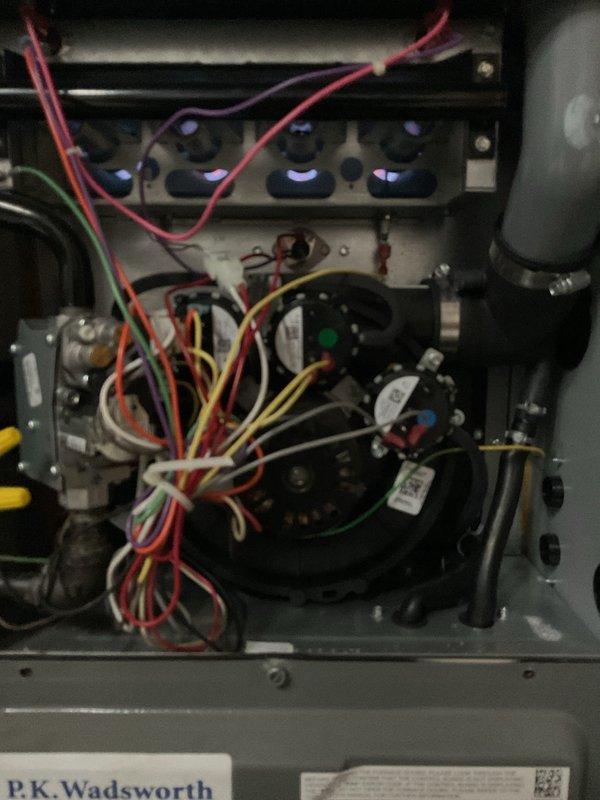 Completed annual preventative maintenance on residential gas furnace as part of scheduled service plan visit. Upon inspection, verified all burners igniting properly with characteristic blue flame pattern, confirmed proper operation of ignition system and flame sensor, and tested safety controls including pressure switches and limit switches. Examined electrical connections throughout the unit, ensuring all wire terminations were secure and showed no signs of overheating or deterioration. Inspected heat exchanger for cracks or signs of failure, checked blower motor operation and capacitor condition, and verified gas valve functionality. All mechanical and electrical components found to be operating within normal parameters with no immediate service needs identified. Documentation photos captured for service records showing active burner operation and overall system condition.