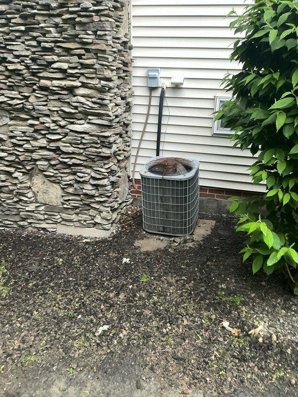 Conducted on-site evaluation of existing HVAC system and provided comprehensive replacement options for residential air conditioning equipment. Documented current system configuration including outdoor condensing unit with protective grille positioned on exterior concrete pad adjacent to stone chimney, electrical disconnect and conduit installation on vinyl siding, and indoor components with service port access. Assessed equipment condition, verified system specifications via unit identification labels and QR codes, and presented multiple replacement alternatives to address cooling needs.