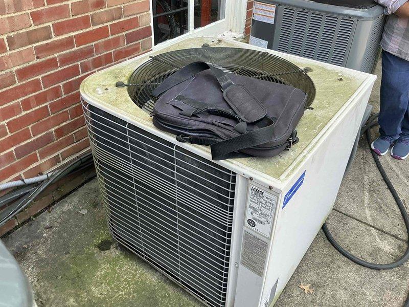 Conducted on-site assessment of existing outdoor air conditioning condenser unit to provide replacement options. Documented current equipment condition, noting weathered housing, aged components, and system specifications visible on manufacturer label. Captured detailed photographs of unit placement, surrounding concrete pad with visible deterioration, and proximity to building structure for accurate replacement planning and equipment sizing recommendations.