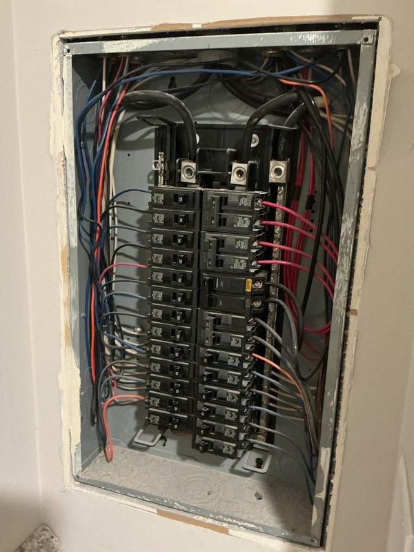 Performed comprehensive electrical inspection of residential service panel and associated systems. Documented main distribution panel containing approximately 30-40 circuit breakers across two columns, verified proper wire routing and connections to bus bars and terminals, and assessed overall panel condition showing normal operational wear. Inspected Bradford White Defender water heater installation including electrical connections, expansion tank mounting, and associated copper plumbing and conduit configurations to ensure code compliance and safe operation.